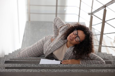 Photo of Injured woman on stairs in building after fall. Dangerous accident