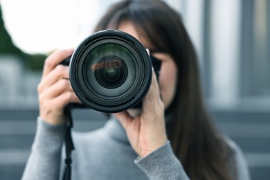 Photo of Professional photographer taking picture with camera outdoors, selective focus