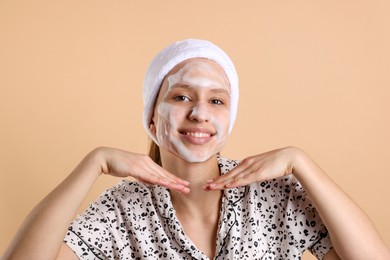 Photo of Teenage girl washing her face with cleanser on beige background. Cosmetic product