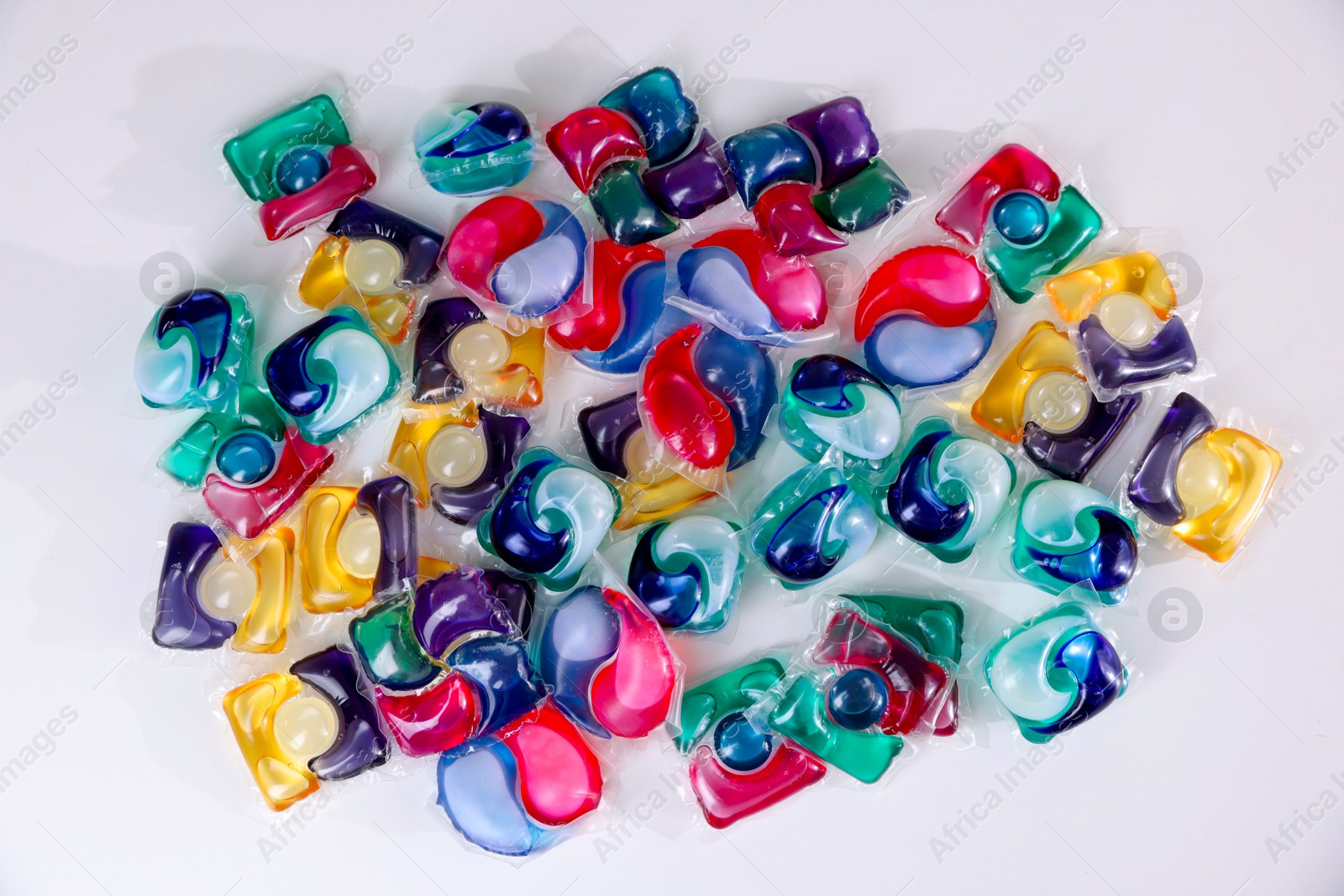 Photo of Different laundry detergent capsules on white background, top view