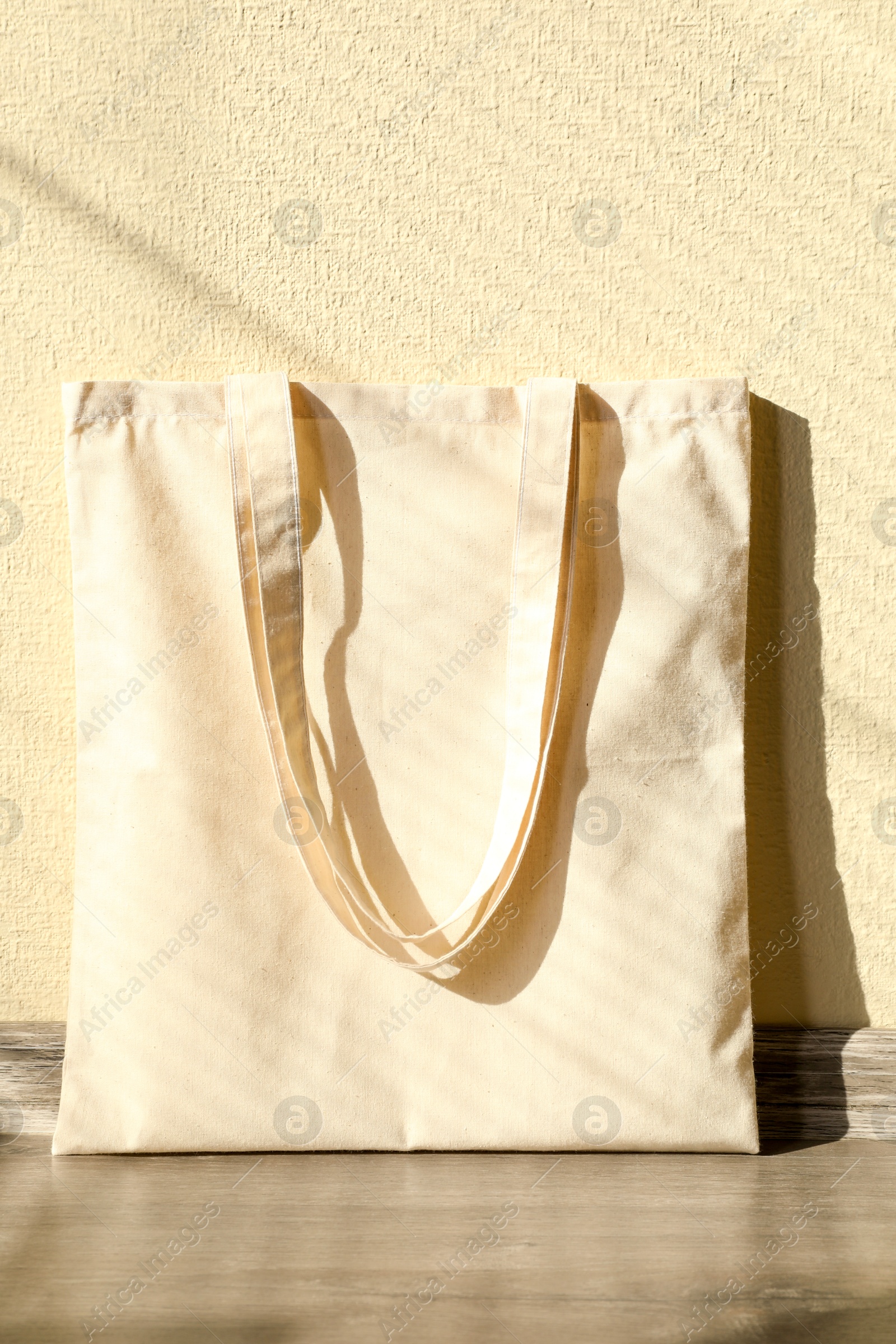 Photo of One eco bag on floor near beige wall. Mockup for design