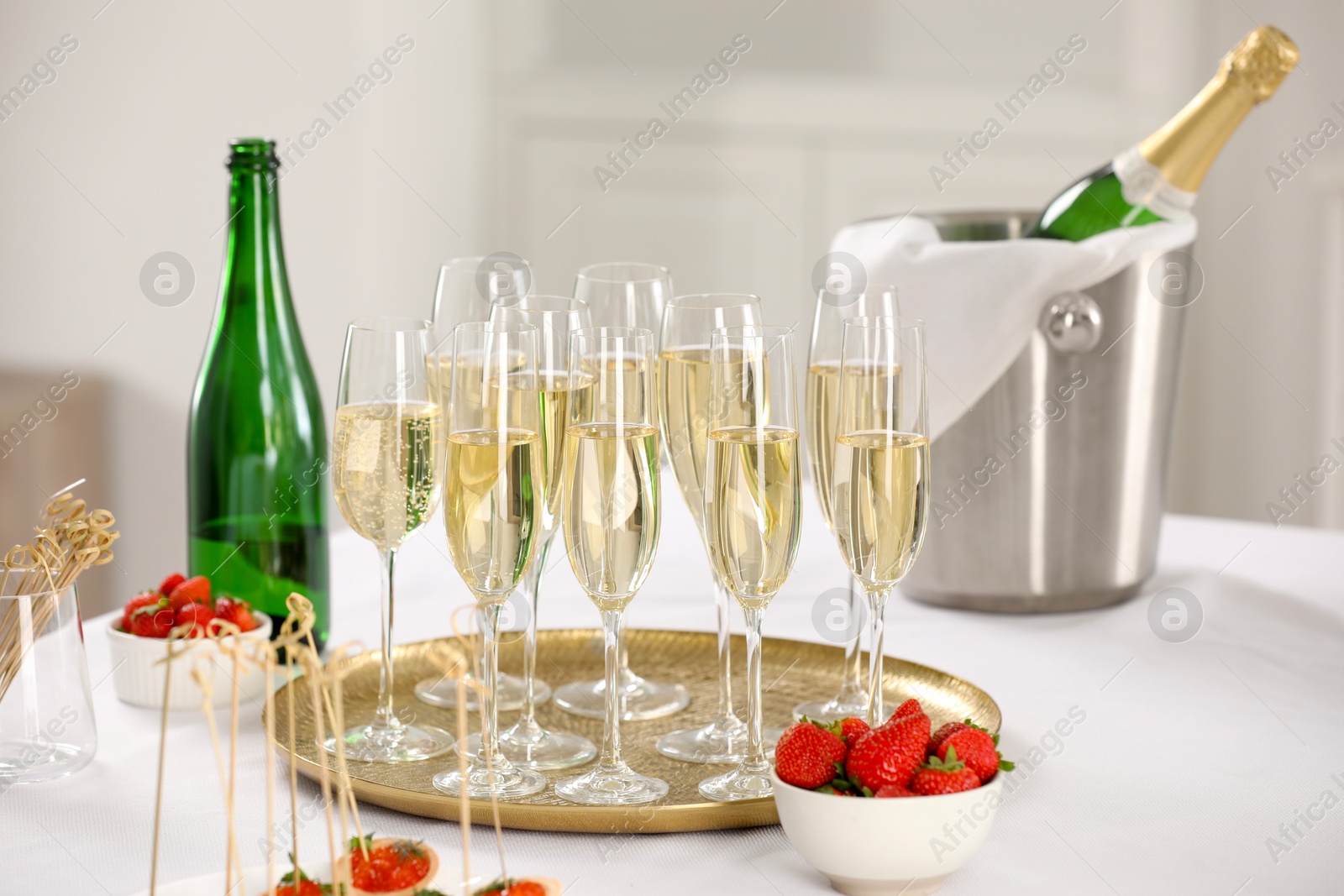 Photo of Champagne, strawberries and canapes on white table