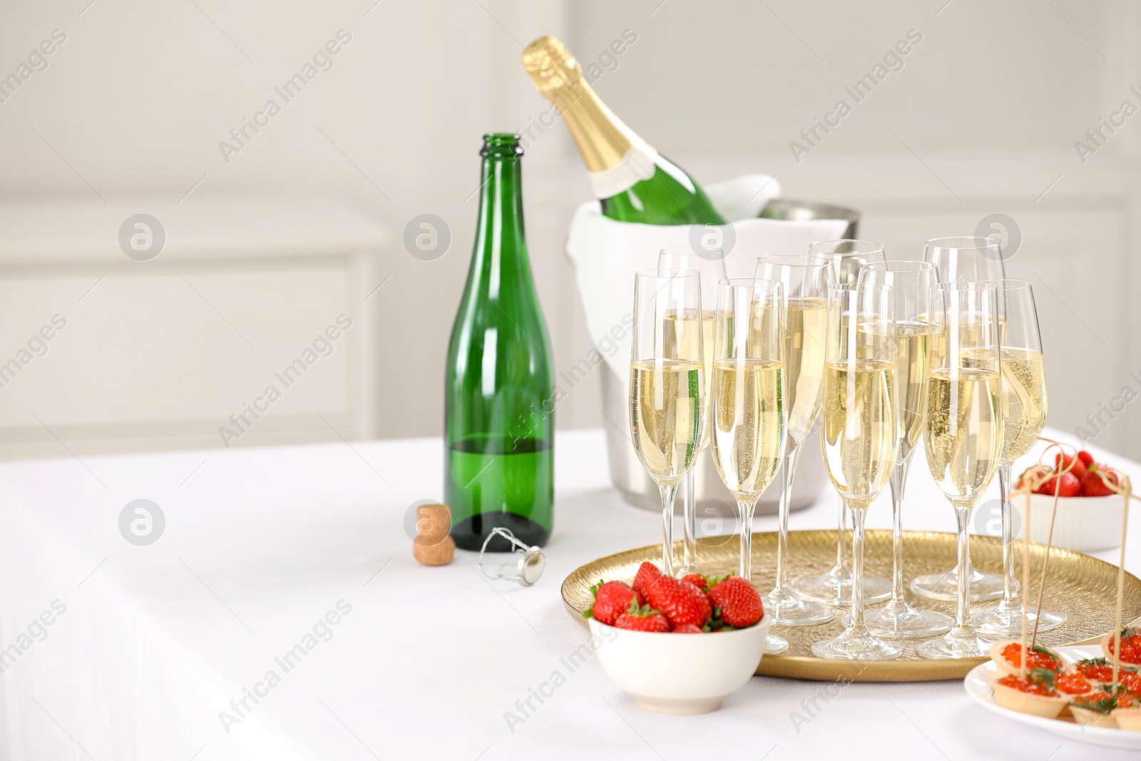 Photo of Champagne, strawberries and canapes with red caviar on white table. Space for text