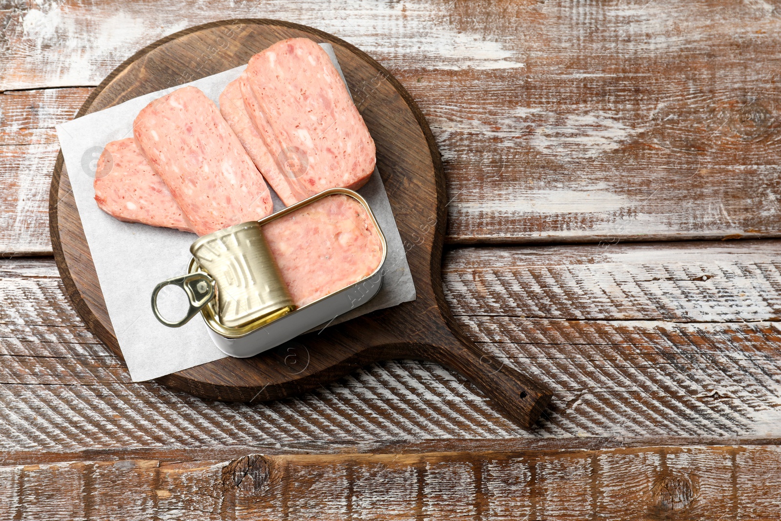 Photo of Tasty canned meat on wooden table, top view. Space for text