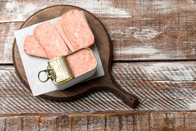 Tasty canned meat on wooden table, top view. Space for text