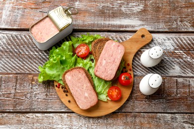 Photo of Tasty canned meat, bread, tomatoes, spices and lettuce on wooden table, top view