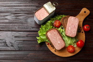 Tasty canned meat, bread, tomatoes, spices and lettuce on wooden table, top view. Space for text