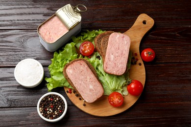 Tasty canned meat, bread, tomatoes, spices and lettuce on wooden table, top view