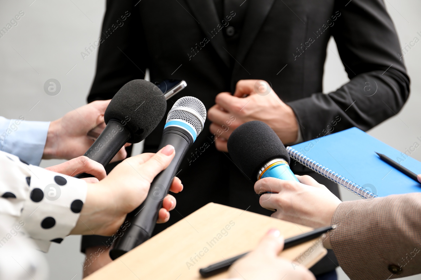 Photo of Group of journalists interviewing businessman on grey background, closeup