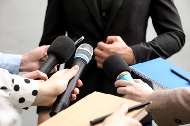 Photo of Group of journalists interviewing businessman on grey background, closeup