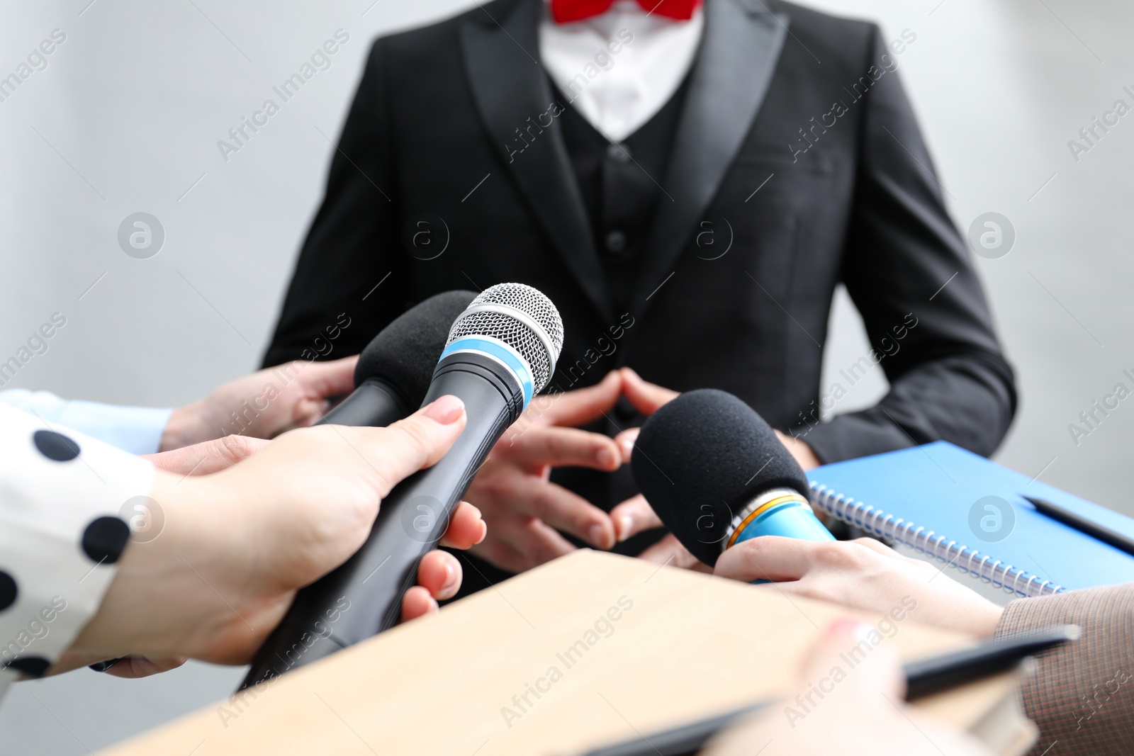 Photo of Group of journalists interviewing businessman on grey background, closeup