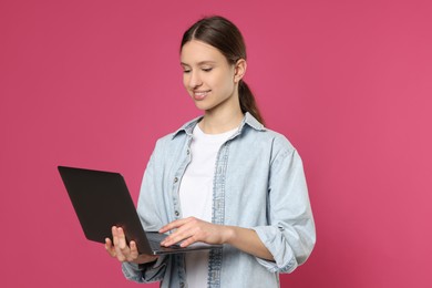 Photo of Portrait of smiling teenage girl with laptop on pink background