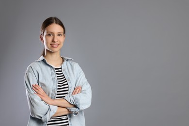 Photo of Portrait of smiling teenage girl with crossed arms on grey background. Space for text