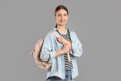 Photo of Portrait of smiling teenage girl with backpack on grey background