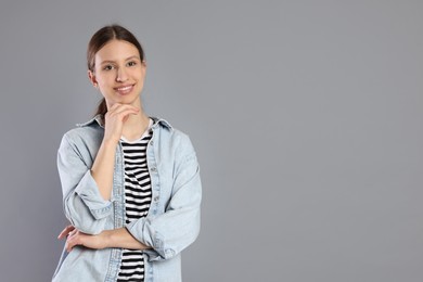 Photo of Portrait of smiling teenage girl on grey background. Space for text