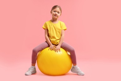 Photo of Cute little girl with fitness ball on pink background