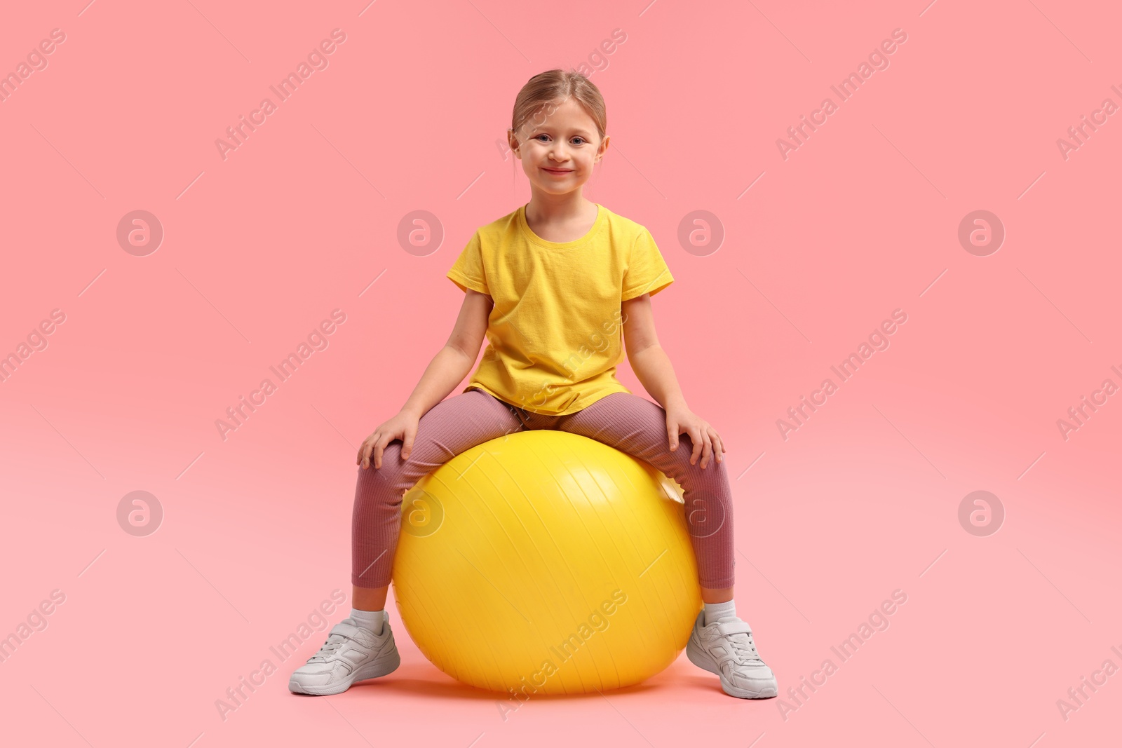 Photo of Cute little girl with fitness ball on pink background