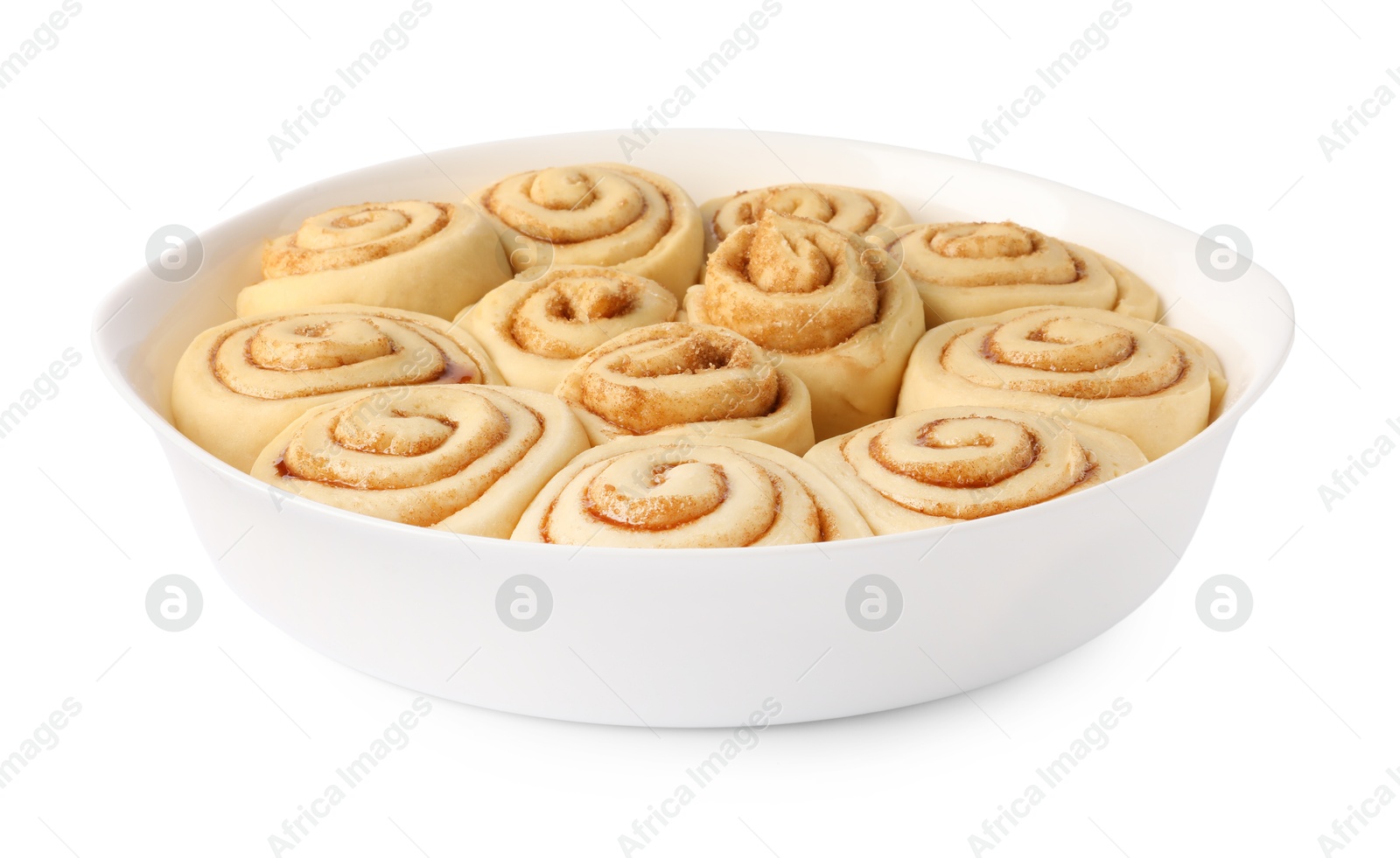 Photo of Raw cinnamon rolls in baking dish isolated on white