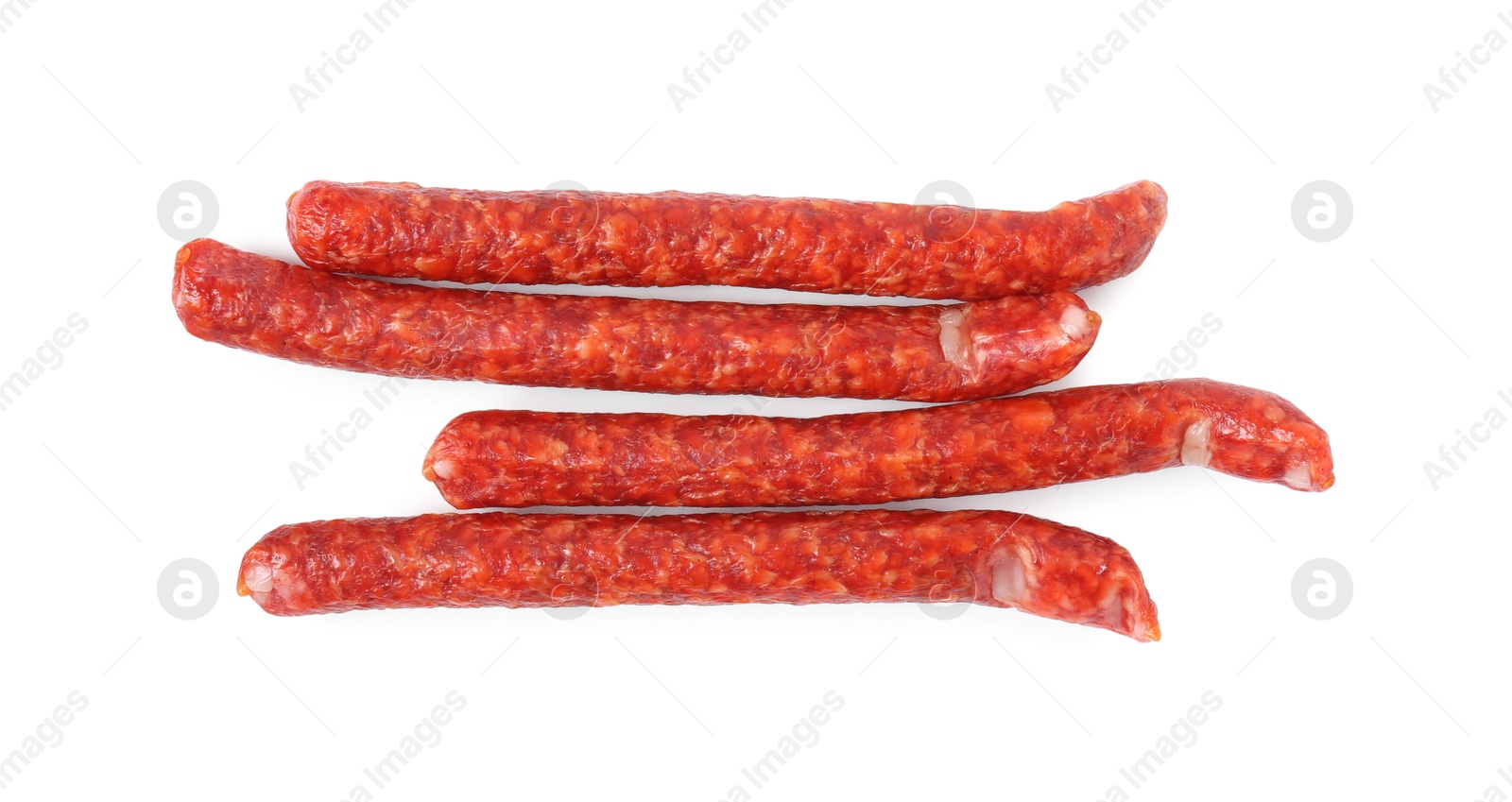 Photo of Many thin dry cured sausages isolated on white, top view