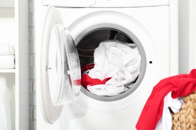 Photo of Washing machine and basket with laundry indoors, closeup