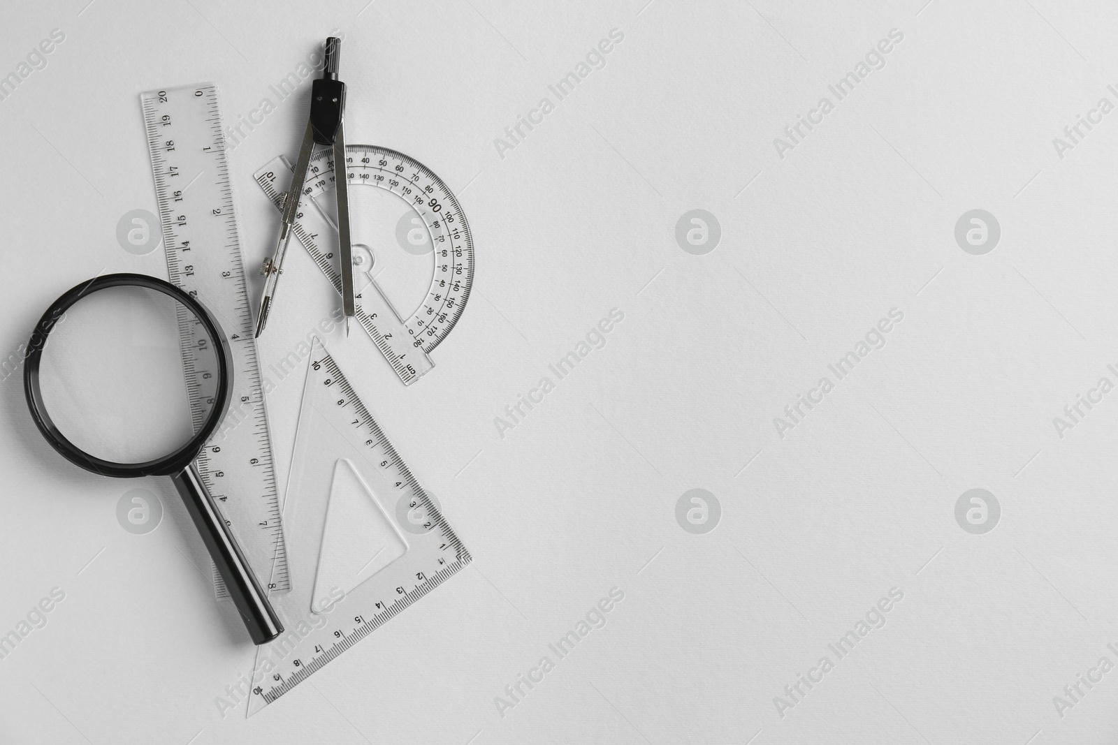 Photo of Rulers, magnifier and compass on light grey background, flat lay. Space for text