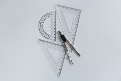 Photo of Rulers and compass on light grey background, flat lay