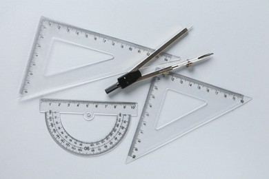 Photo of Rulers and compass on light grey background, flat lay