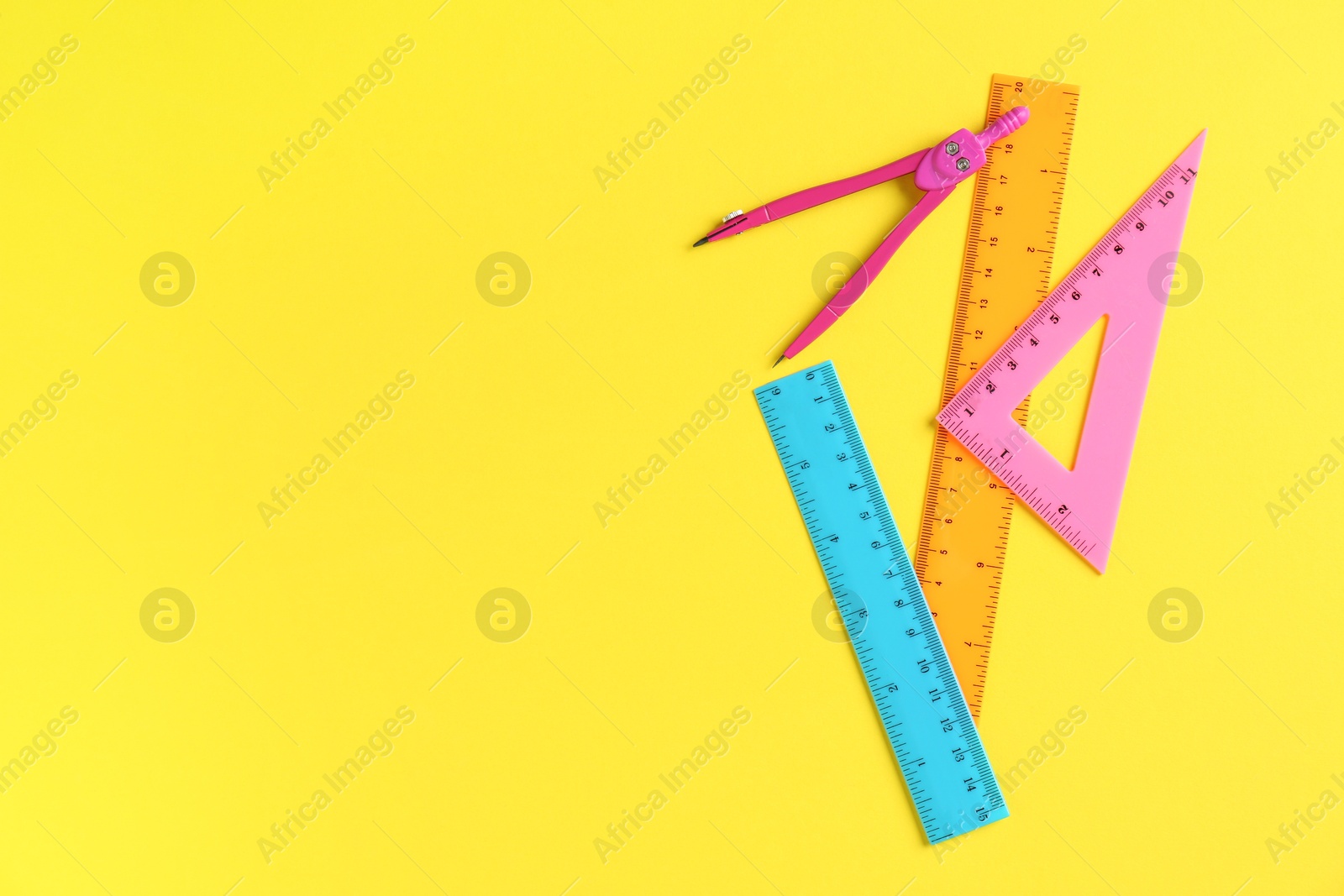 Photo of Rulers and compass on yellow background, flat lay. Space for text