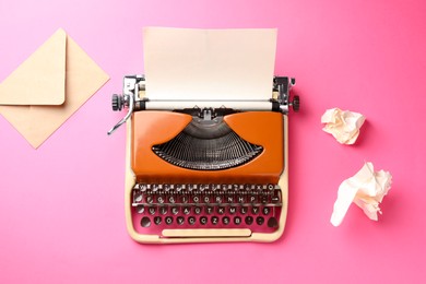 Photo of Vintage typewriter, crumpled paper and envelope on pink background, flat lay