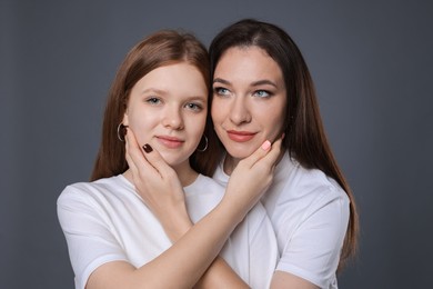 Photo of Portrait of beautiful mother with teenage daughter on grey background