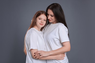 Photo of Portrait of beautiful mother with teenage daughter on grey background