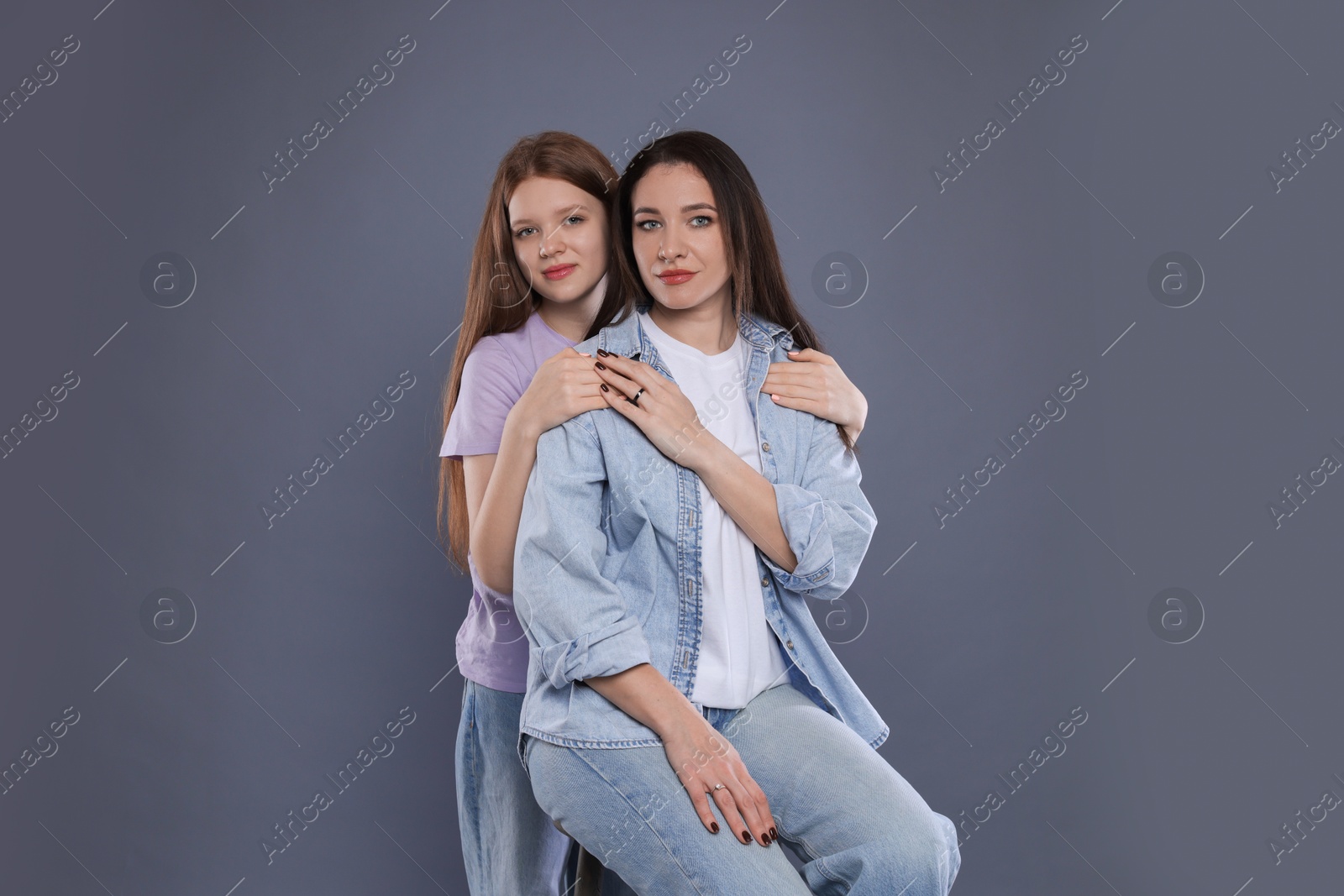 Photo of Portrait of beautiful mother with teenage daughter on grey background