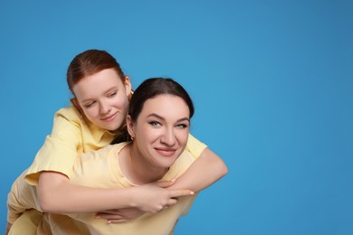 Photo of Portrait of beautiful mother with teenage daughter on light blue background, space for text