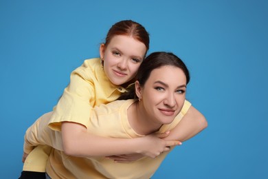 Photo of Portrait of beautiful mother with teenage daughter on light blue background