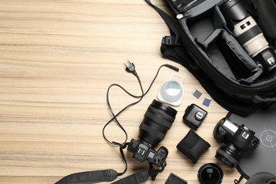 Photographer's equipment on wooden background, flat lay. Space for text