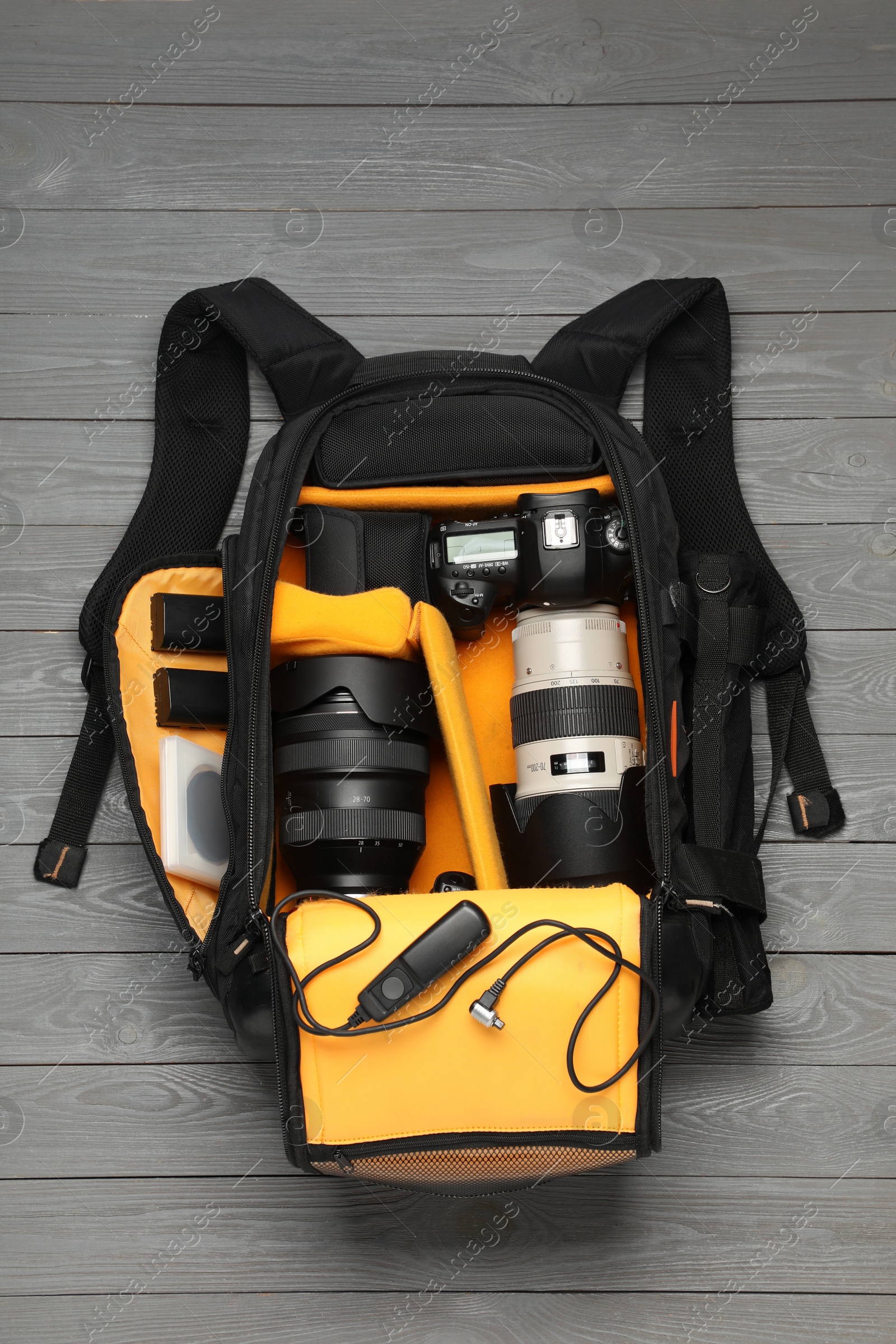 Photo of Professional photographer's equipment and backpack on grey wooden background, flat lay