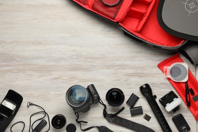 Photo of Professional photographer's equipment and backpack on light wooden background, flat lay. Space for text