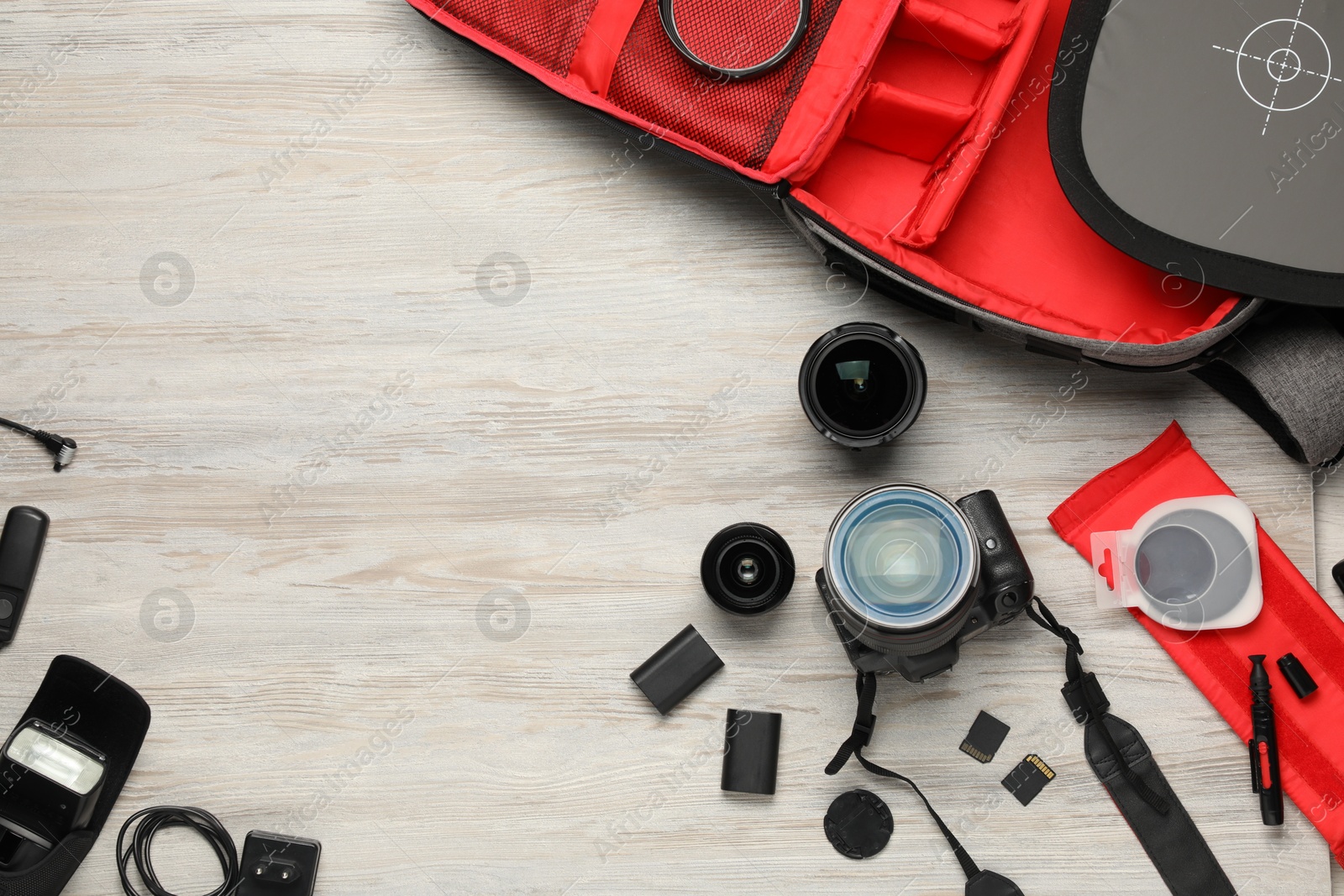 Photo of Professional photographer's equipment and backpack on light wooden background, flat lay. Space for text