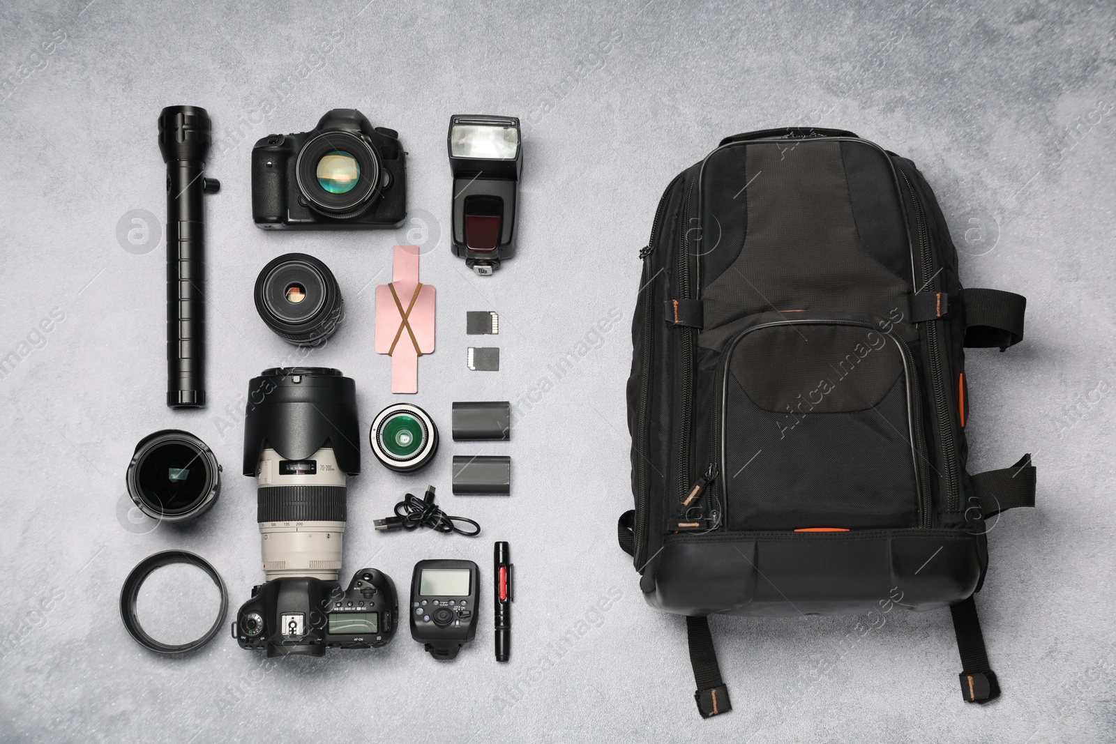 Photo of Professional photographer's equipment and backpack on light background, flat lay