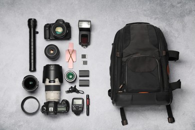 Professional photographer's equipment and backpack on light background, flat lay