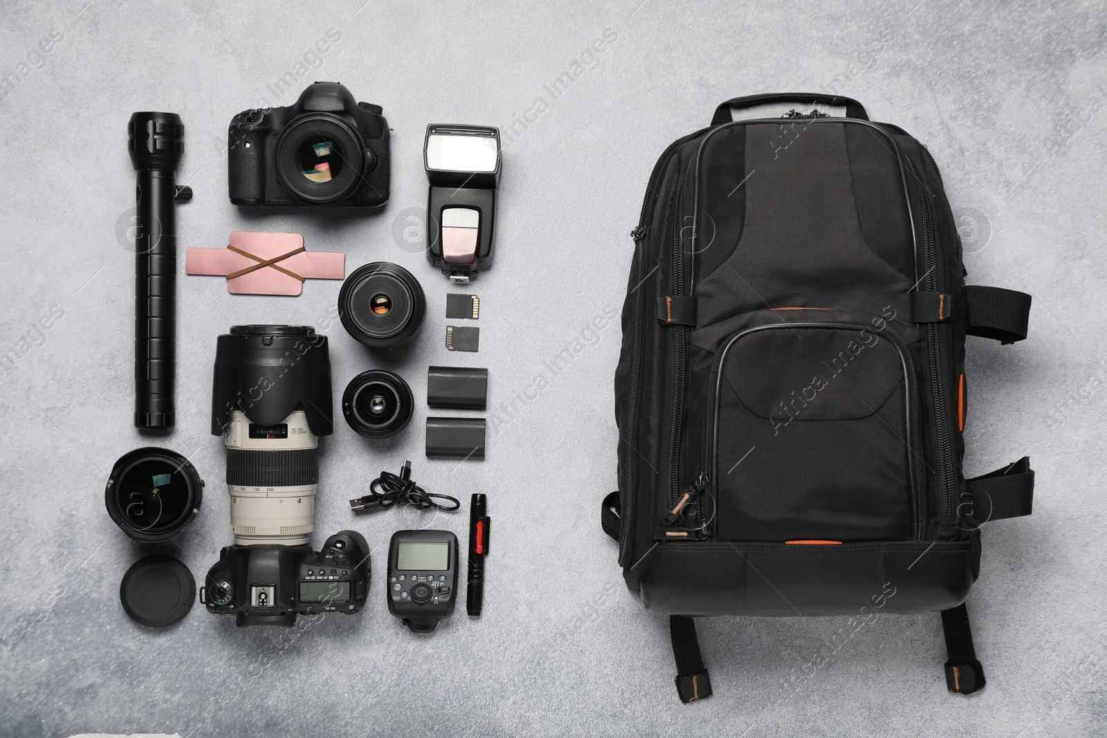 Photo of Professional photographer's equipment and backpack on light background, flat lay