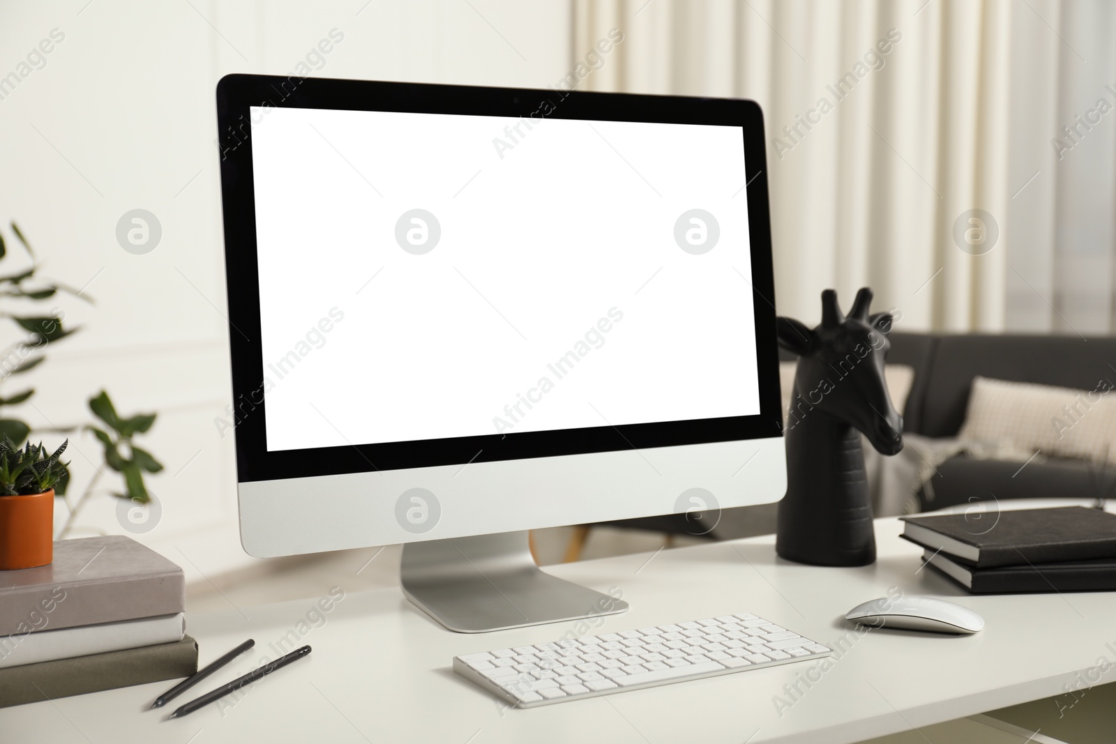 Photo of Modern workplace with computer and stationery on white desk indoors