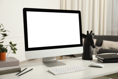 Photo of Modern workplace with computer and stationery on white desk indoors