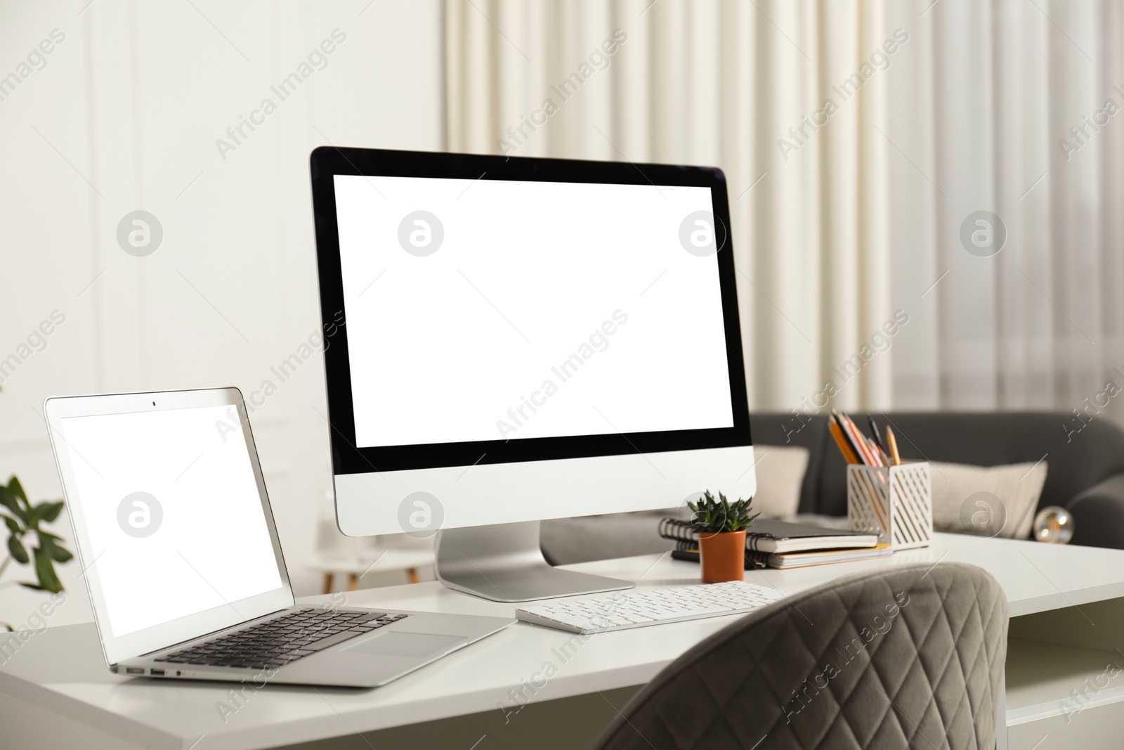 Photo of Modern workplace with computer and laptop on white desk indoors