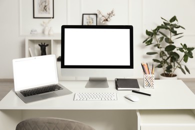 Photo of Modern workplace with computer and laptop on white desk indoors