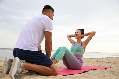 Photo of Couple doing exercise together on beach. Body training