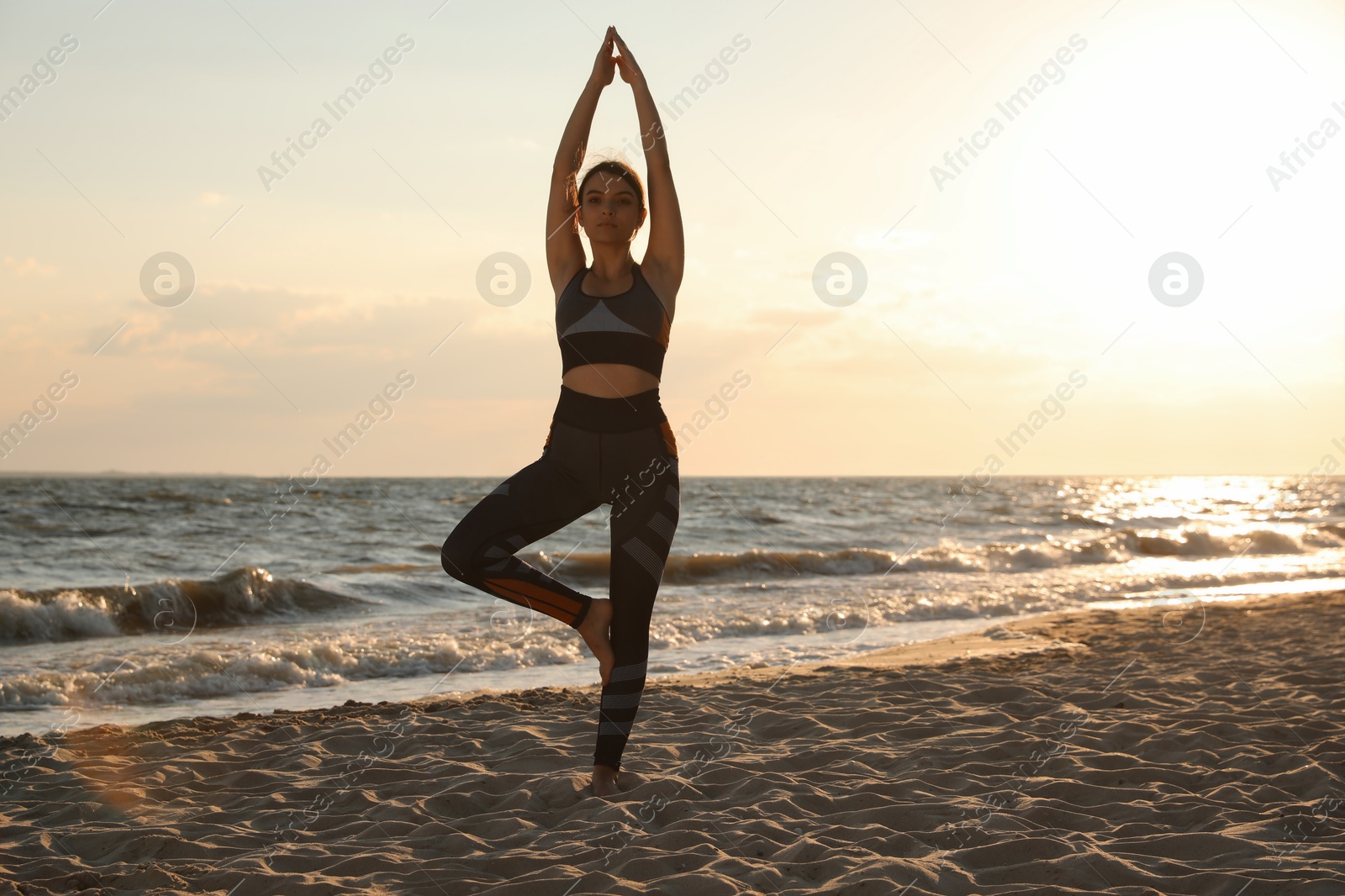 Photo of Young girl with slim body doing yoga on beach