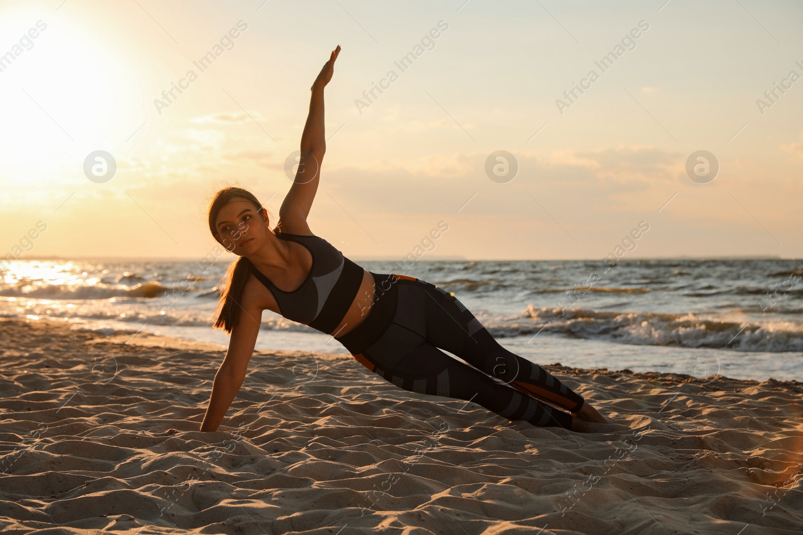 Photo of Young girl with slim body doing yoga on beach