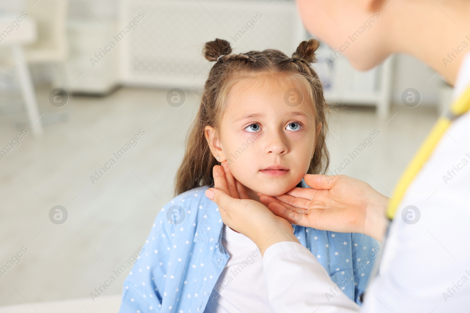 Photo of Doctor examining girl's throat in clinic during appointment