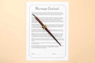 Marriage contract, pen and golden rings on beige background, top view